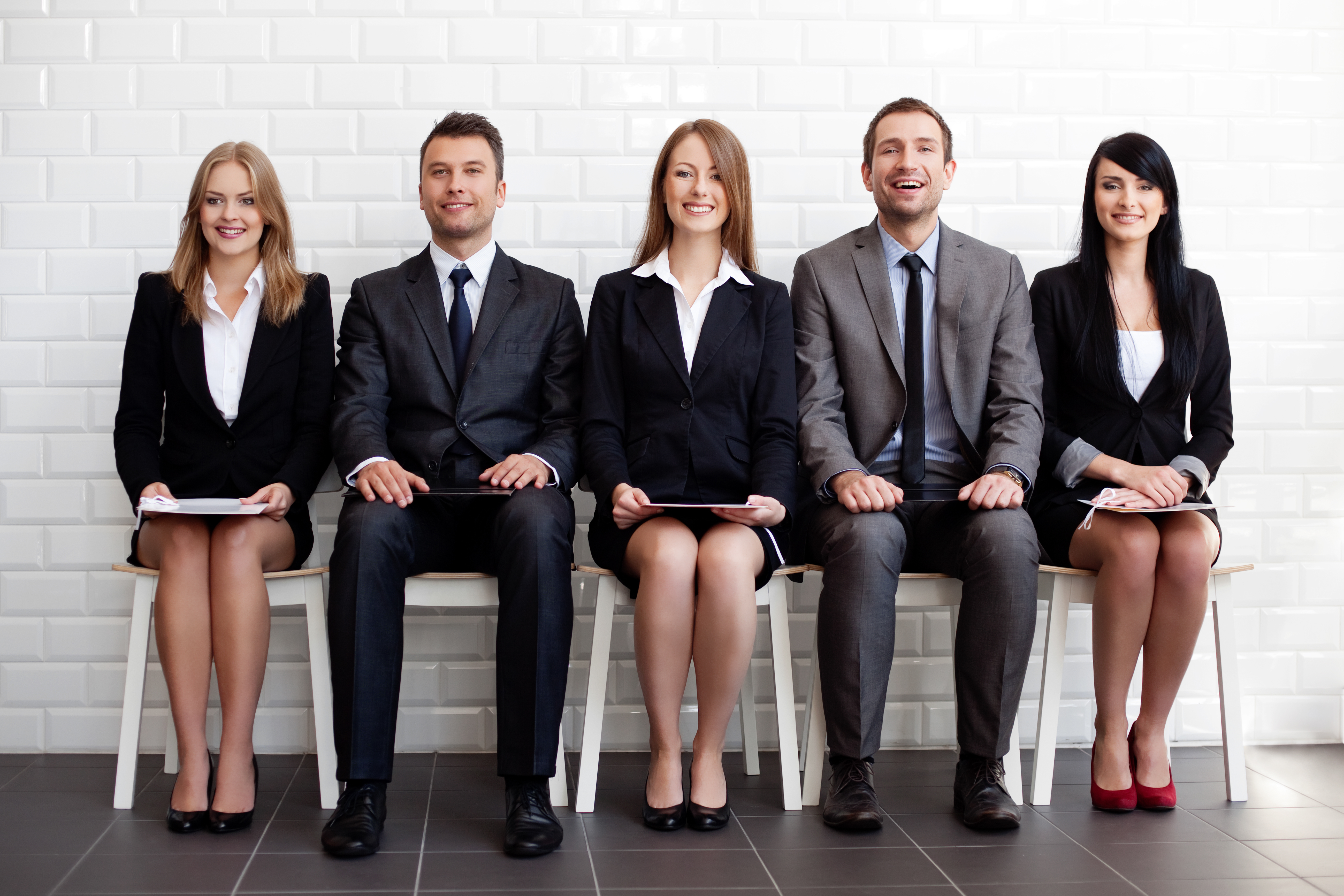 A picture that shows three women and two men in suits, seated in the correct posture with positive body language.