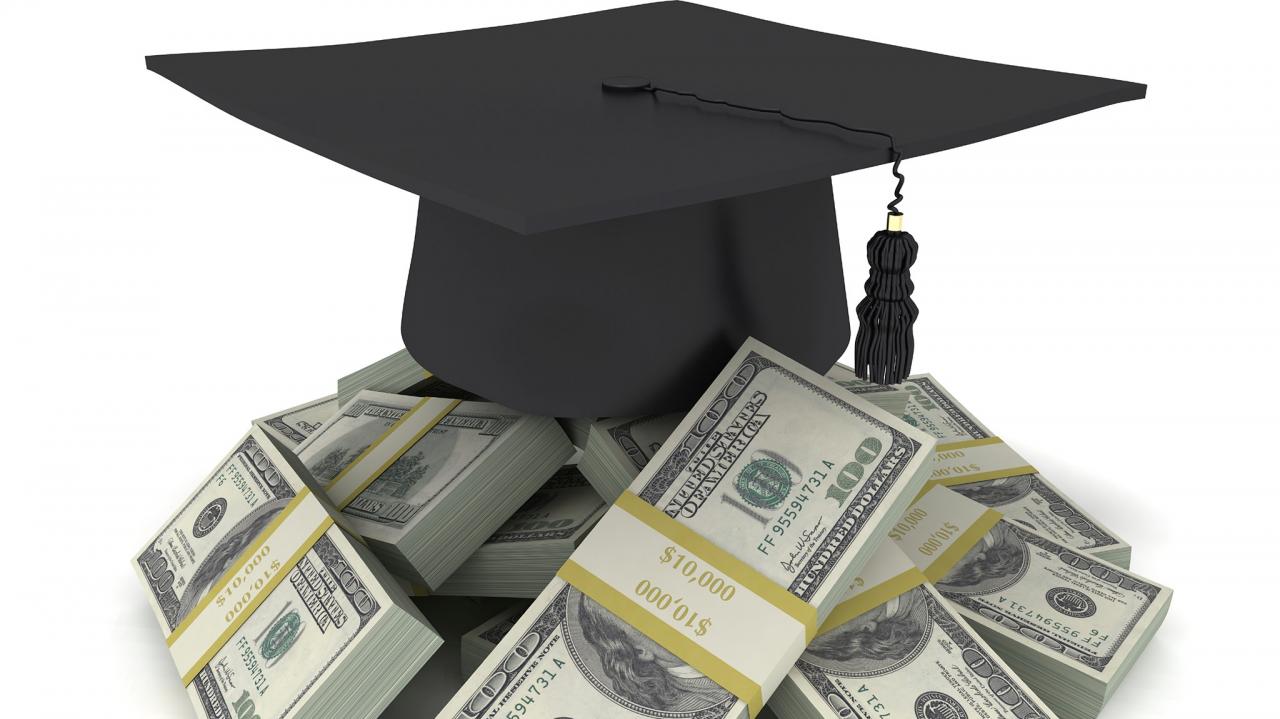 A graduation cap placed on a pile of money symbolic of the importance given to ROI while selecting MBA colleges